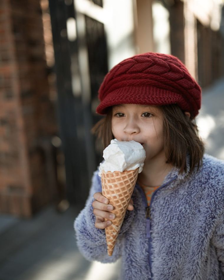 A young girl smiling while eating an ice cream cone